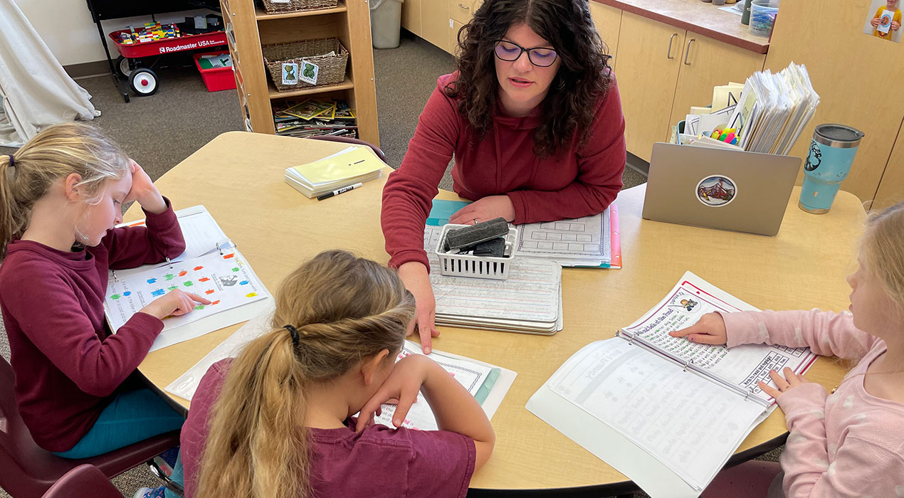 first grade teacher working on literacy skills with 3 students