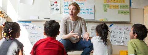 Teacher explains a concept to four students facing her